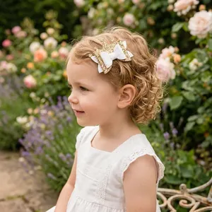 Glitter crown bow hair clip worn by a little girl in a beautiful garden setting.