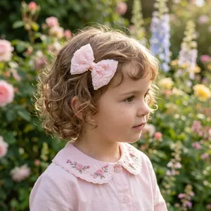 Detail shot of a little girl wearing a beautiful pink lace bow hair clip in a garden