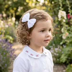 Elegant white lace bow hair clip for girls shown on a child in a garden setting