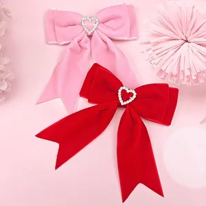 Close-up detail of red and pink velvet bow hair clips with sparkling rhinestone hearts.