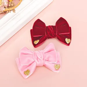 Close-up of velvet bow hair clips with gold glitter hearts in red and pink colors
