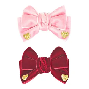 Detail view of pink and burgundy velvet bow hair clips with gold glitter hearts for girls