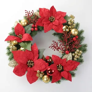 Close-up of a Christmas wreath with red poinsettia flowers and gold baubles