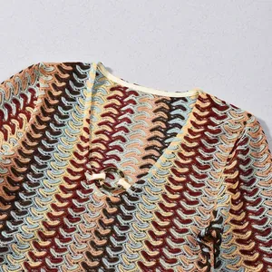Detailed close-up of V-neckline with golden ring on colorful wave pattern knit dress