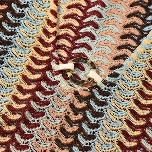 Close-up of multicolored knit texture and gold ring detail on slim fit dress