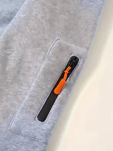 Macro view of bright orange zipper pull on light blue fleece-lined hoodie pocket