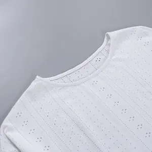 Gros plan sur le tissu blanc ajouré d'un haut de pyjama à manches longues avec col rond chic