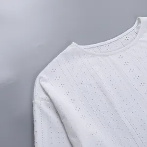 Vue détaillée d'un haut blanc à manches longues pour femmes avec motifs ajourés et broderies