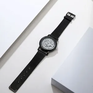 Minimalist black quartz watch with a skeleton dial design and black mesh strap detail