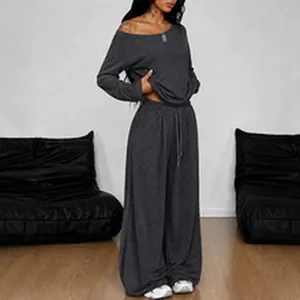 Woman wearing a charcoal grey two-piece lounge set with off-shoulder top and wide-leg pants.