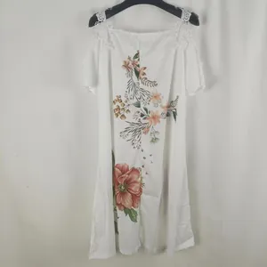 Detalle de vestido blanco con estampado floral, hombros descubiertos y encaje fino
