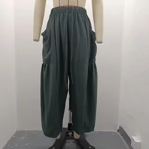Detail view of dark green pleated cotton linen trousers on a studio display mannequin.