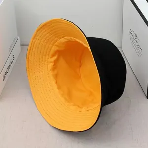 Detailed view of a reversible double-sided fisherman bucket hat in black and yellow