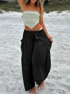 Detail of black cotton linen wide-leg trousers featuring elastic waist and pleated texture.