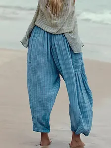 Detail of the textured fabric on women's blue pleated cotton linen cropped pants on beach