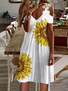 Detalle de un vestido blanco de verano con girasoles estampados y hombros fríos de encaje.