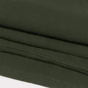 Macro detail of stitching and fabric texture on a dark green men's Renaissance shirt.