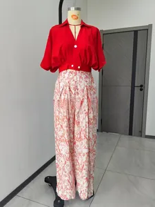 Ensemble d'été deux pièces avec chemisier rouge à col en V et pantalon large fleuri.