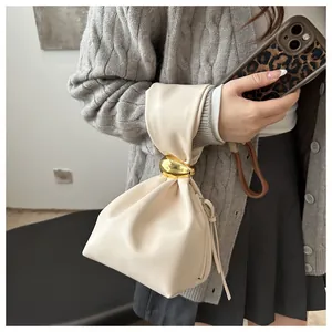 Detailed view of a cream pleated handbag with gold hardware accent