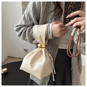 Close-up of a vintage cream-colored pleated bucket bag with gold hardware detail.