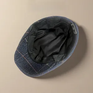 Interior detail of retro herringbone wool flat cap showing black lining and snaps