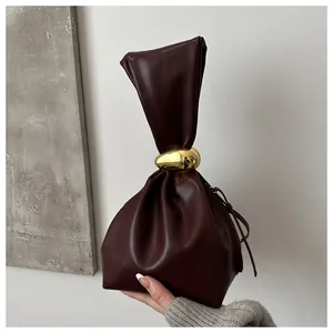 Detail of a burgundy pleated leather bucket bag featuring elegant gold hardware.
