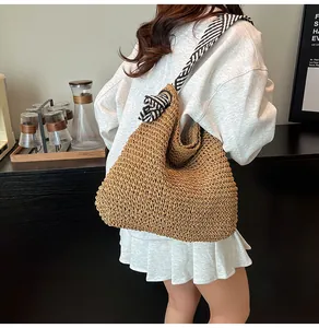 Detailed back view of a large woven straw bag with a stylish striped shoulder strap