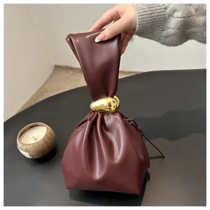 Close-up of vintage burgundy pleated handbag with a unique gold metal buckle design