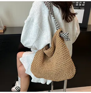 Back view of a large straw woven tote bag with navy striped strap