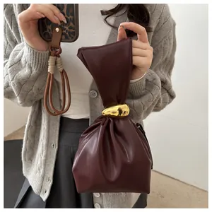 Close-up of a burgundy vintage pleated bucket bag featuring a gold metallic ring handle
