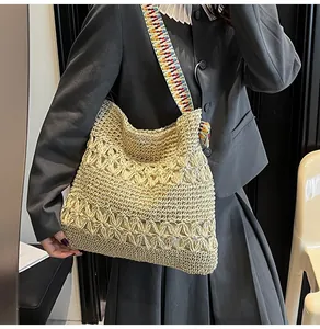 Detail of a large straw woven tote bag with a colorful geometric patterned strap.