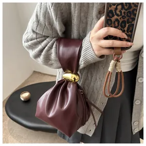 Close-up showing the soft pleated texture and gold metal ring on a wine red bucket bag