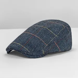 Detail view of a blue herringbone wool flat cap featuring a retro British plaid pattern