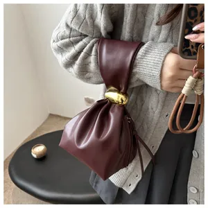 Detailed close-up of a burgundy pleated bucket bag with a stylish gold ring handle