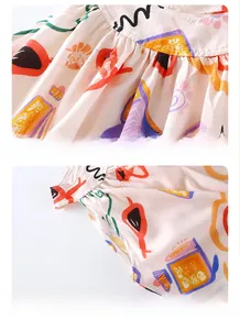 Detail view of girl's summer dress featuring artistic colorful print and pleated design.