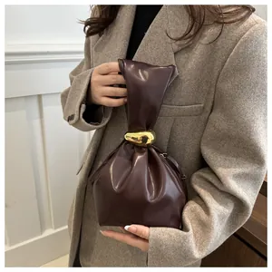 Detailed view of a retro pleated dark brown bucket bag with gold metal buckle