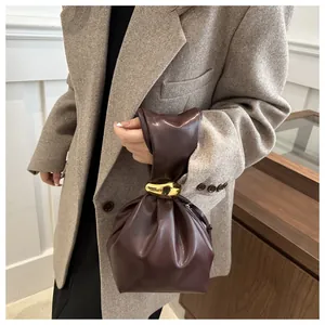 Detail view of vintage brown pleated bucket bag with chic gold ring handle detail.