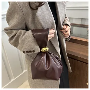 Detailed view of a retro pleated brown faux leather bucket bag with a gold buckle.