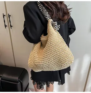 Detail view of a nautical style woven straw tote bag with wide striped shoulder strap