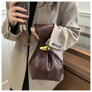 Detailed view of brown retro pleated bucket bag with gold ring handle and blazer.