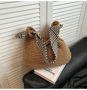 Detail of a straw tote bag with a nautical black and white striped shoulder strap.