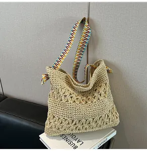 Macro view of woven straw tote bag with a colorful bohemian patterned wide strap.