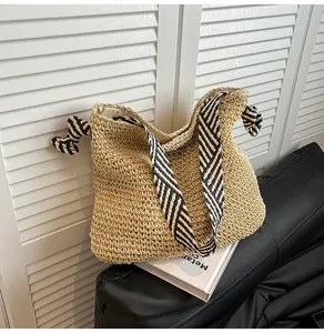 Macro view of handmade straw woven tote bag featuring navy striped wide straps for summer