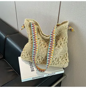 Detailed view of the hand-woven texture and colorful strap of this straw tote bag.