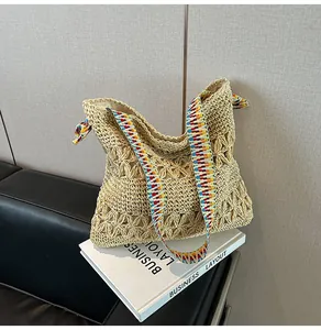 Detailed view of a handmade straw woven tote bag featuring a colorful geometric strap.