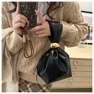 Close-up of a vintage black pleated bucket bag with gold ring detail held by model