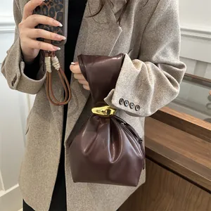 Chic retro brown pleated leather bucket bag with gold hardware held by a female model.