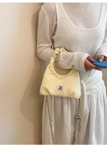 Cute cream yellow ruffled handbag with bear patch worn by a model in a minimal setting