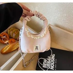 Detail shot of a pink ruffled handbag with lace trim and a cute bear patch detail.