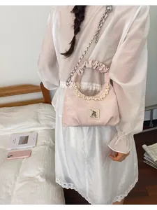 Woman in white dress carrying a cute pink pleated shoulder bag with delicate lace details